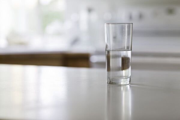 Vaso de agua con rodaja de limón en una superficie clara