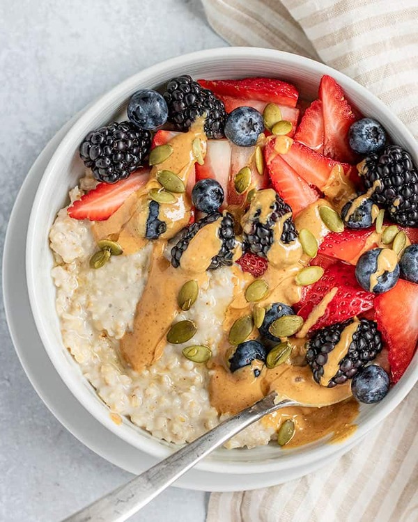 Mesa iluminada con fruta fresca, yogur y granola listos para un desayuno sencillo